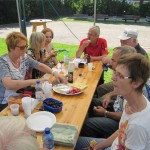 Personen an Biertisch mit Essen und Getränken